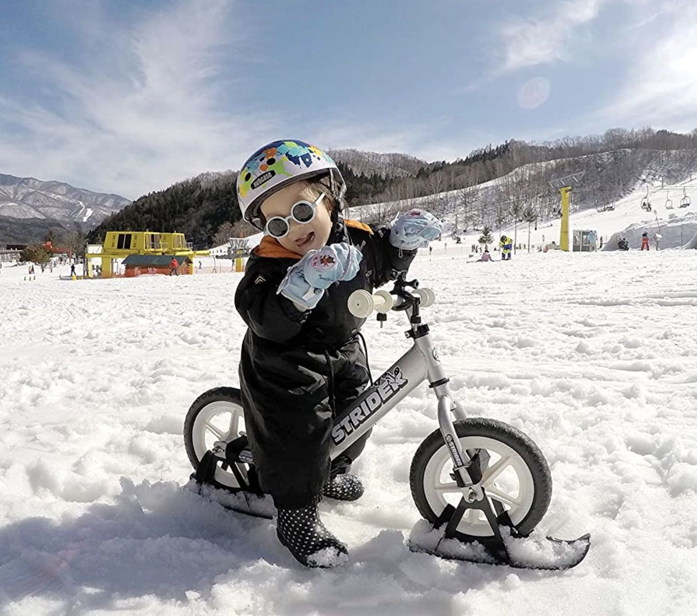 Niño montando sobre la nieve con su complemento de esquís para la bicicleta sin pedales Strider Sport