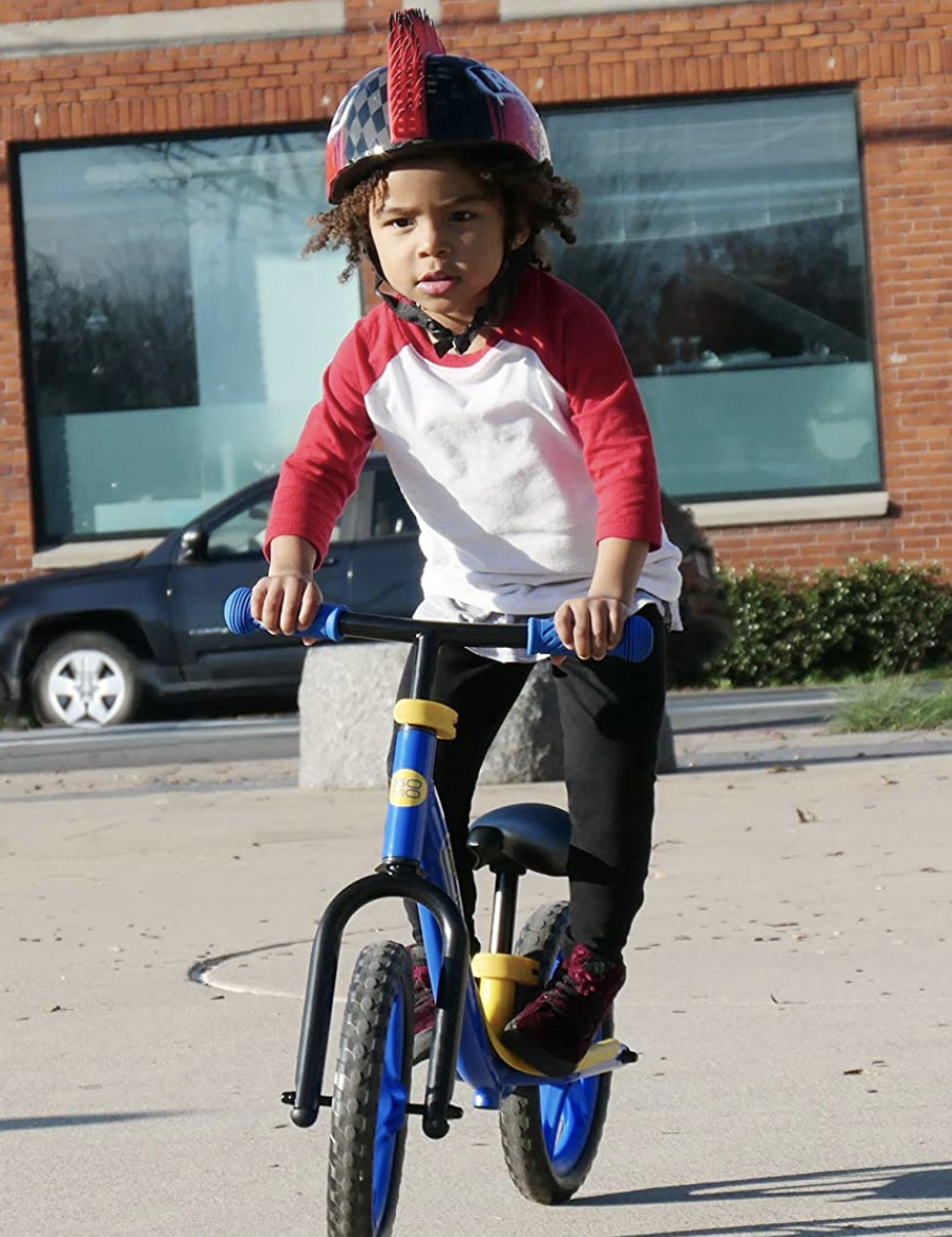 Niño sobre el reposapies de su bicicleta sin pedales Gomo